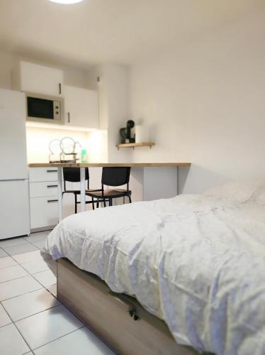 une chambre blanche avec un lit et une cuisine dans l'établissement T1 rénové à Nîmes, à Nîmes