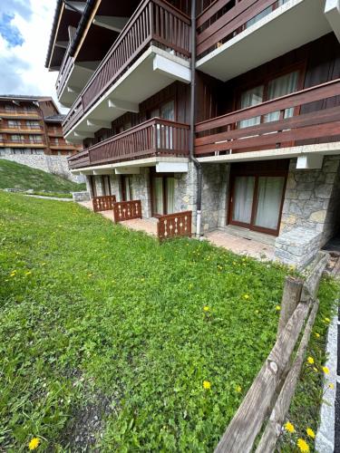 un bâtiment avec une pelouse verte devant lui dans l'établissement Appartement rez de jardin au pied des pistes, à Les Allues