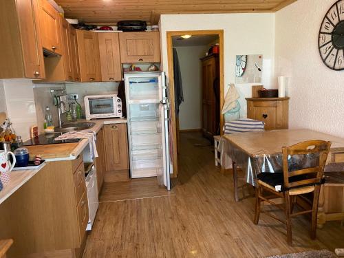 une petite cuisine avec une table et un réfrigérateur dans l'établissement Appartement rez de jardin au pied des pistes, à Les Allues