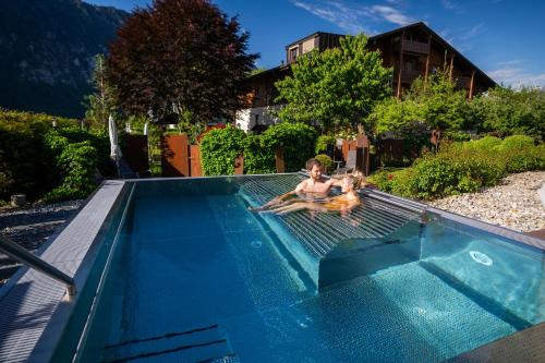 two people sitting in a swimming pool at SALZANO Hotel - Spa - Restaurant in Interlaken