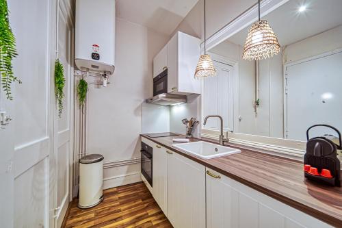 La cuisine est équipée de placards blancs, d'un lavabo et d'un miroir. dans l'établissement La Grande Suite Championnet - Calme & Confort, à Grenoble