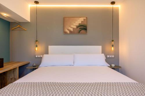 Un dormitorio con una cama blanca con luces encima. en paqo lodge Laguna del Portil, a 400 metros de la playa, en El Portil