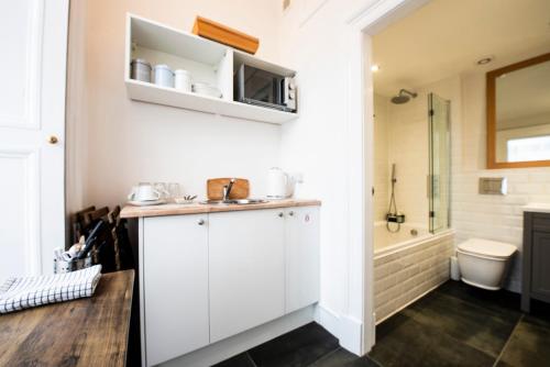 łazienka z białymi szafkami, toaletą i prysznicem w obiekcie Sheen's House w Edynburgu