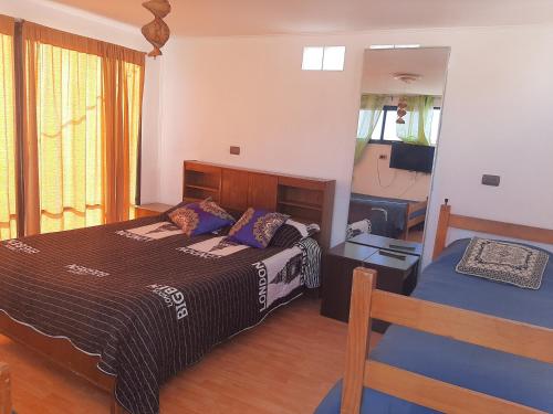 - une chambre avec un grand lit et un miroir dans l'établissement Hostal Pampaloja, à Antofagasta