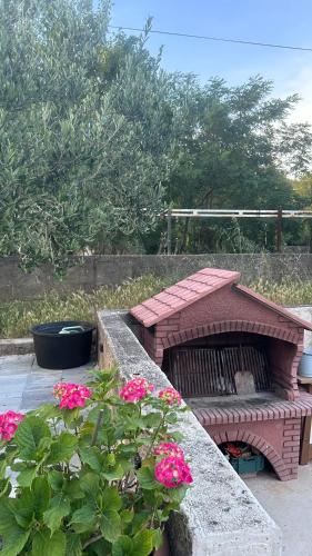 a brick fire pit in a garden with pink flowers at Apartment Lora in Starigrad-Paklenica