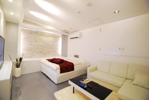 a bedroom with a bed and a couch at Hotel Free Style Okayama in Okayama