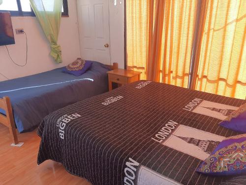 a bedroom with two beds and a window with curtains at Hostal Pampaloja Antof in Antofagasta