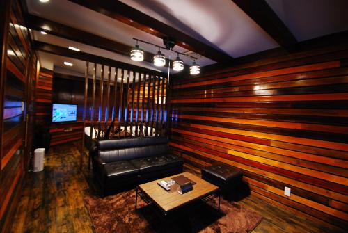 a living room with a leather couch and a table at Hotel Free Style Okayama in Okayama