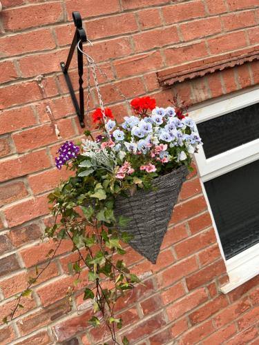 een mand met bloemen aan een stenen muur bij The Red Lion 