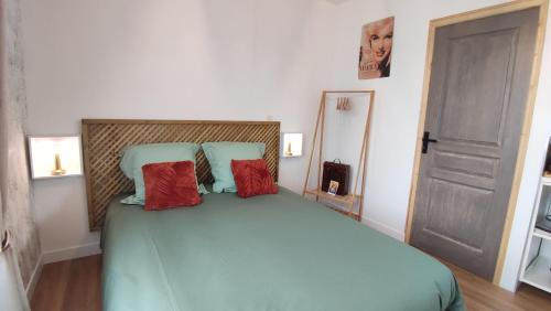 a bedroom with a large bed with two red pillows at Studio jardin st jean de daye in Saint-Jean-de-Daye