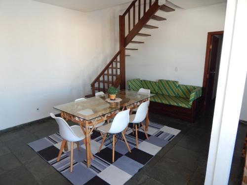 a dining room with a wooden table and white chairs at Cobertura de 3 Quartos Duplex in Cabo Frio