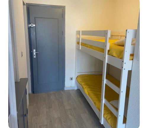 Cette chambre comprend 2 lits superposés et une porte bleue. dans l'établissement Studio le cap d agde piscine et tennis, au Cap d'Agde