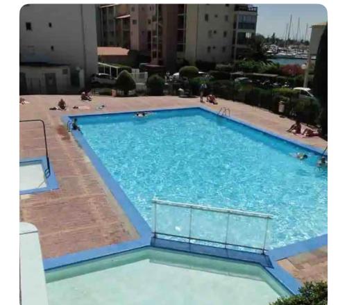 une grande piscine avec de l'eau bleue dans un immeuble dans l'établissement Studio le cap d agde piscine et tennis, au Cap d'Agde