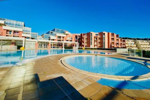 une grande piscine avec des bâtiments en arrière-plan dans l'établissement 557 Cap Corniche Front de mer Clim Parking, à Sète