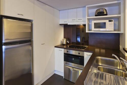 a kitchen with white cabinets and a stainless steel refrigerator at The Chancellor on Hobson in Auckland