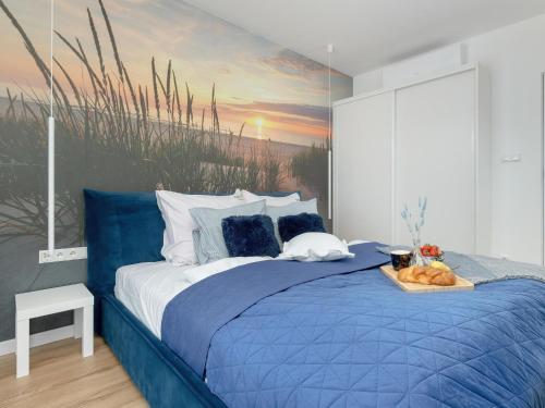 a bedroom with a blue bed with a painting on the wall at Beautiful apartment overlooking the river, swimming pool, sauna, Dziwnów in Dziwnów