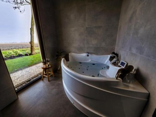 uma banheira na casa de banho com uma janela em Wellness Bungalow with whirlpool and sauna em Zevenhuizen