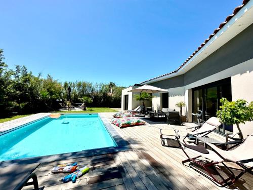 une piscine avec des chaises et une maison dans l'établissement Villa architecte ecume 400m plage, au Cap d'Agde