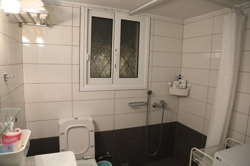 a bathroom with a shower and a toilet and a window at Alimos House in Athens