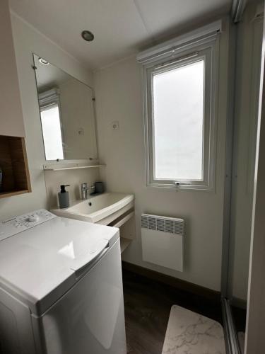a white bathroom with a sink and a mirror at Grand Mobil Home Tout Confort pour 6 personnes - Camping Les Oyats 4 étoiles in Seignosse