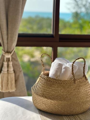 a basket of rolled towels sitting in front of a window at COCCOLOBA in Holbox Island