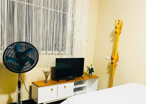 a bedroom with a fan and a tv and a bed at Convenient city apartment with free WiFi in Dar es Salaam