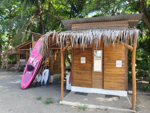 a small wooden shack with a surfboard next to it at Camping Babsita-TIPI und Hütten und Stellplätze für Zelt und Camper direkt am Meer und See in Tuba Creek