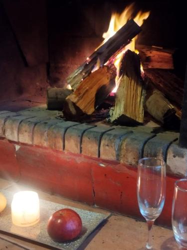 a fireplace with an apple and two glasses on a table at Visión ESCAPE Piriápolis in Piriápolis