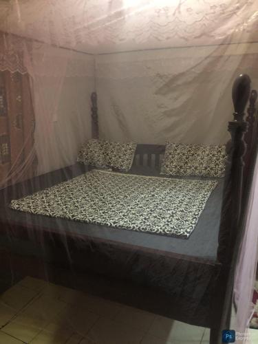 a bed in a room with a canopy at African Taste Guest House. in Kitende