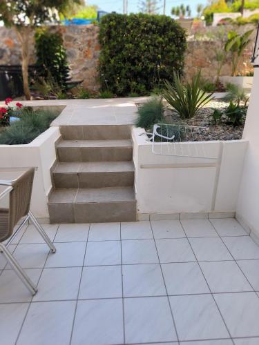 a patio with stairs and a chair and plants at Cost Mari Almyrida New by ZAGO Boutiqe hotels in Almirida