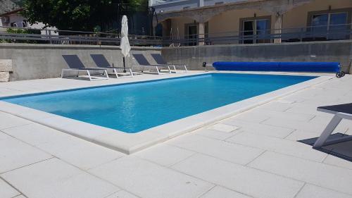 a swimming pool with two chairs and an umbrella at Apartmani Naomi&Leo in Senj