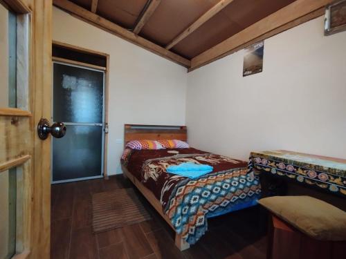 a small bedroom with a bed and a door at Starlight Inn in Sigchos