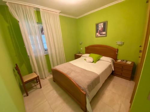 カストロポルにあるBajo apartamentos Casa Paquitaの緑のベッドルーム(ベッド1台、椅子付)