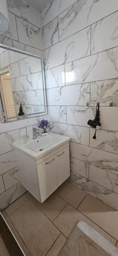 a white bathroom with a sink and a mirror at Apartman Lookman Neum in Neum