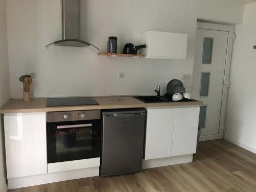 une cuisine avec des armoires blanches et un four noir dans l'établissement Au cœur de la ville, à Lourdes