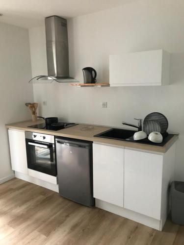 une cuisine avec des armoires blanches et un four à plaques de cuisson dans l'établissement Au cœur de la ville, à Lourdes