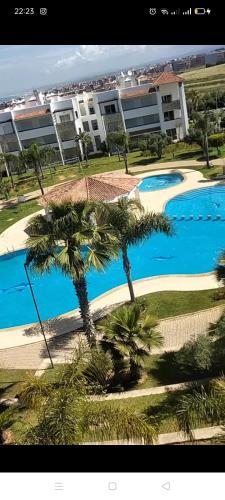 a view of a pool with palm trees and a building at assilah marina golf assilah in Asilah
