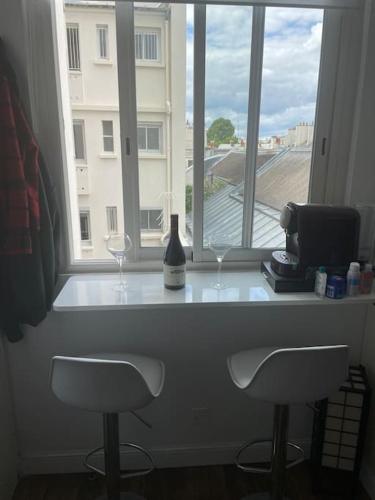 une fenêtre avec deux verres à vin et une bouteille dans l'établissement La perle rare du 7e, à Paris