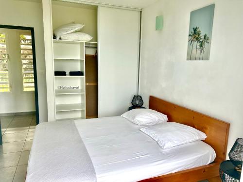 un dormitorio con una cama con sábanas blancas en Villa Tropical Quintet, en Deshaies