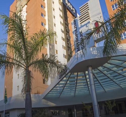 a building with a palm tree in front of it at Suíte premium - Metropolitan Square Hotel in Bauru