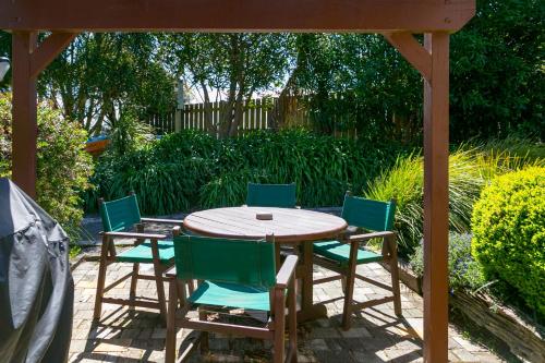a wooden table and chairs under a gazebo at Cascades Lakefront Motel in Taupo