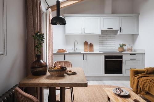 a kitchen with white cabinets and a wooden table at Kittiwake apartment - Coastal, luxury, self-catering in Port Isaac