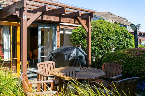 a patio with a wooden table and chairs and a tent at Cascades Lakefront Motel in Taupo