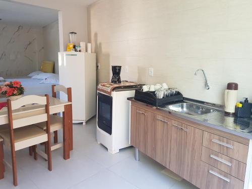 a kitchen with a sink and a refrigerator and a table at Loft em ótima localização in São Lourenço