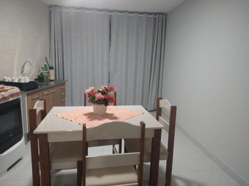 a kitchen with a table with a vase of flowers on it at Loft em ótima localização in São Lourenço