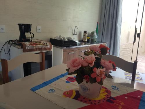 a kitchen with a vase of flowers on a table at Loft em ótima localização in São Lourenço