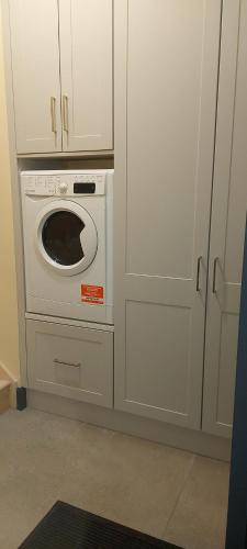 a washer and dryer in a kitchen with white cabinets at Lovely Laois Loft Apartment in Carlow