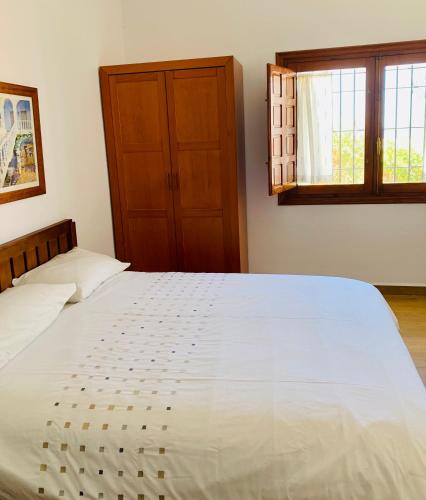 a bedroom with a large white bed and a window at La Barraca B - Descanso Familiar con gran patio en entorno tranquilo cerca del mar in Mojácar