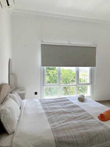 a white bedroom with a large bed with a window at VILLA seeb 2 MIN walk to the beach in Seeb
