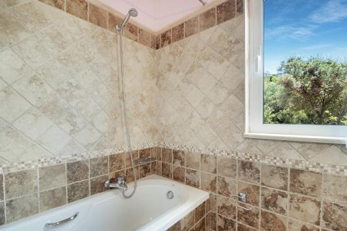 a bathroom with a tub and a window at Villa Belvedere Rosa in Tsoukaladhes